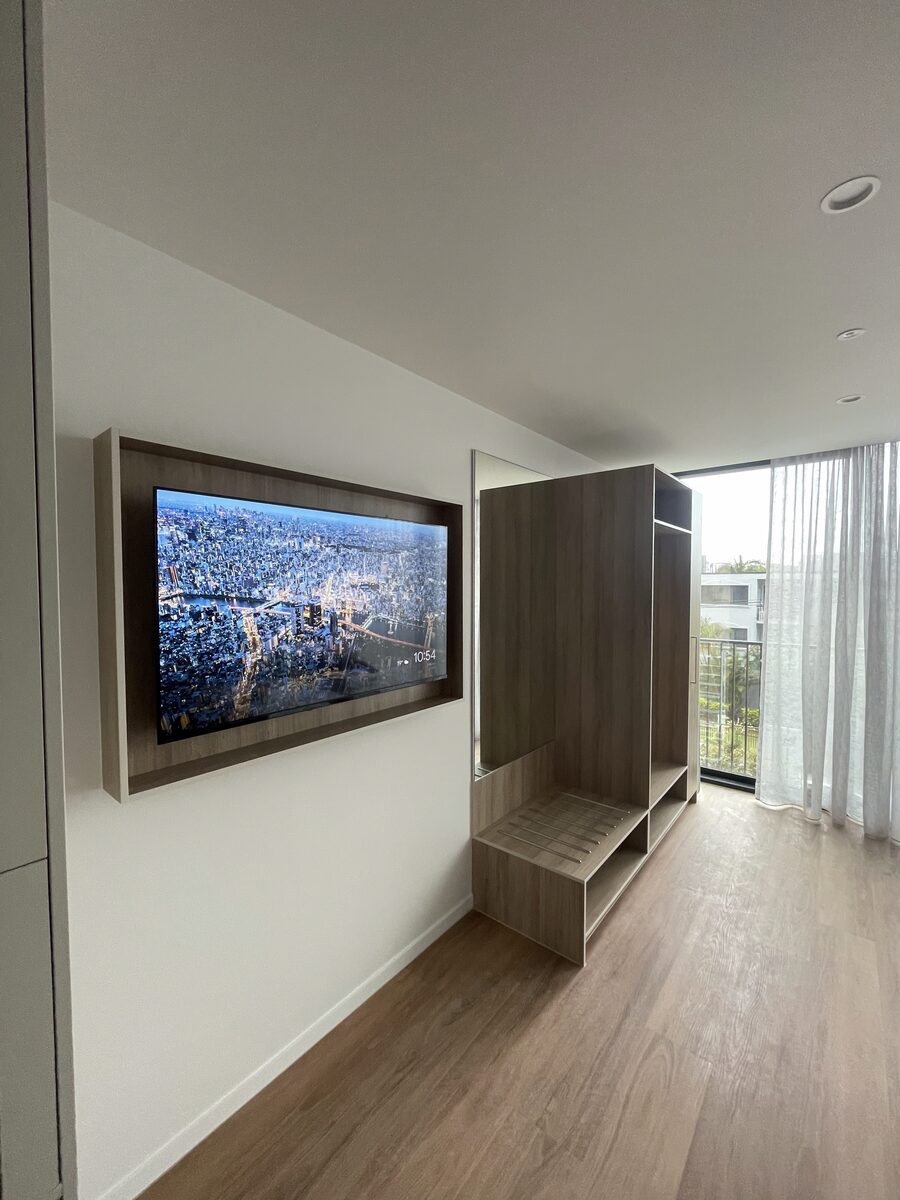 Frame TV wall-mounted within a timber surround, built-in joinery alongside. Cliff Hanger Installations.