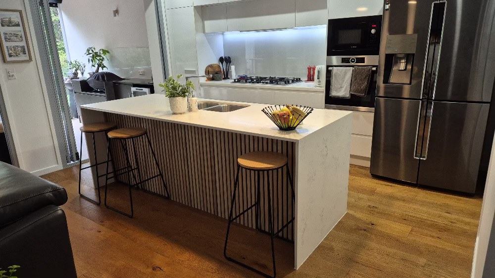 Detail of slat island panel with bar stools, kitchen looking through to lounge.
