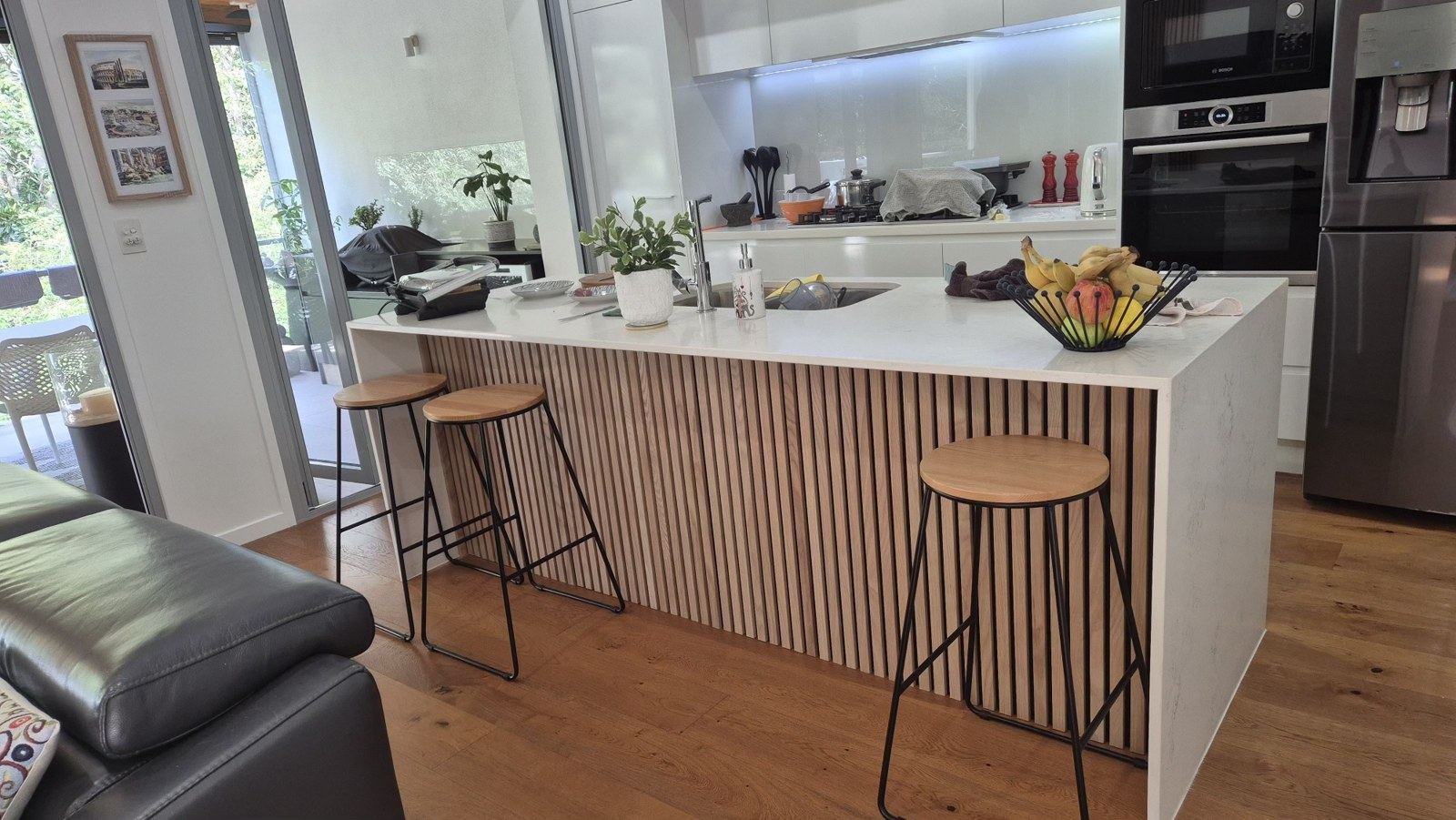 After: same kitchen island finished with a full-height vertical timber slat feature panel.