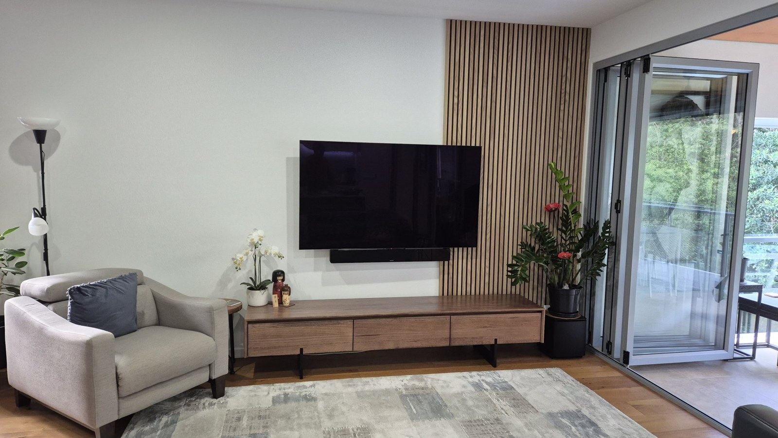 After: the lounge wall finished with a floor-to-ceiling timber slat panel beside the wall-mounted TV.