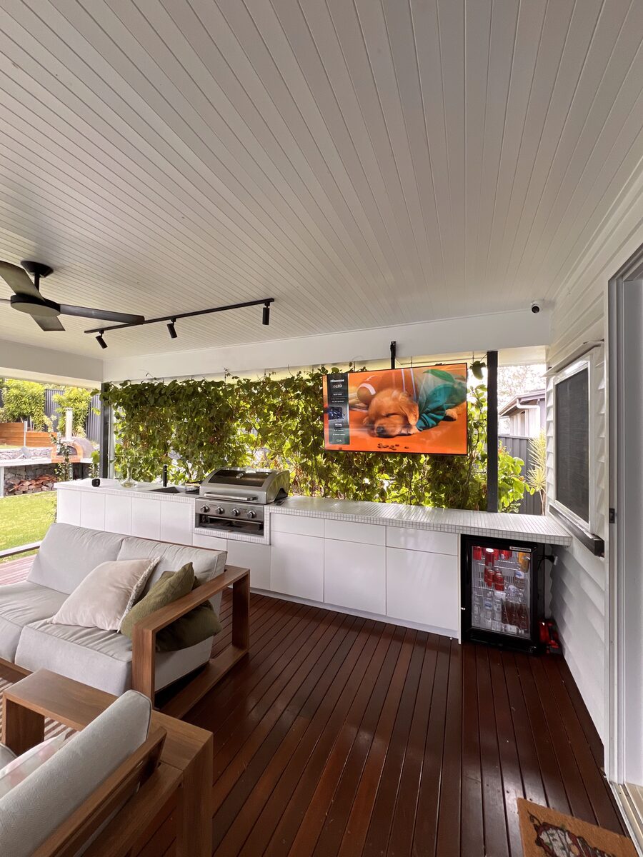 Outdoor-rated TV mounted on a covered patio with cabling run through the soffit.