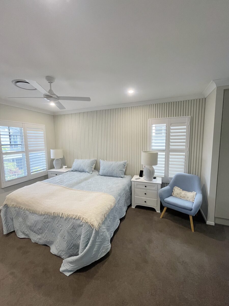 Vertical timber slat wall installed behind a bedhead, set level and tight along the joins.