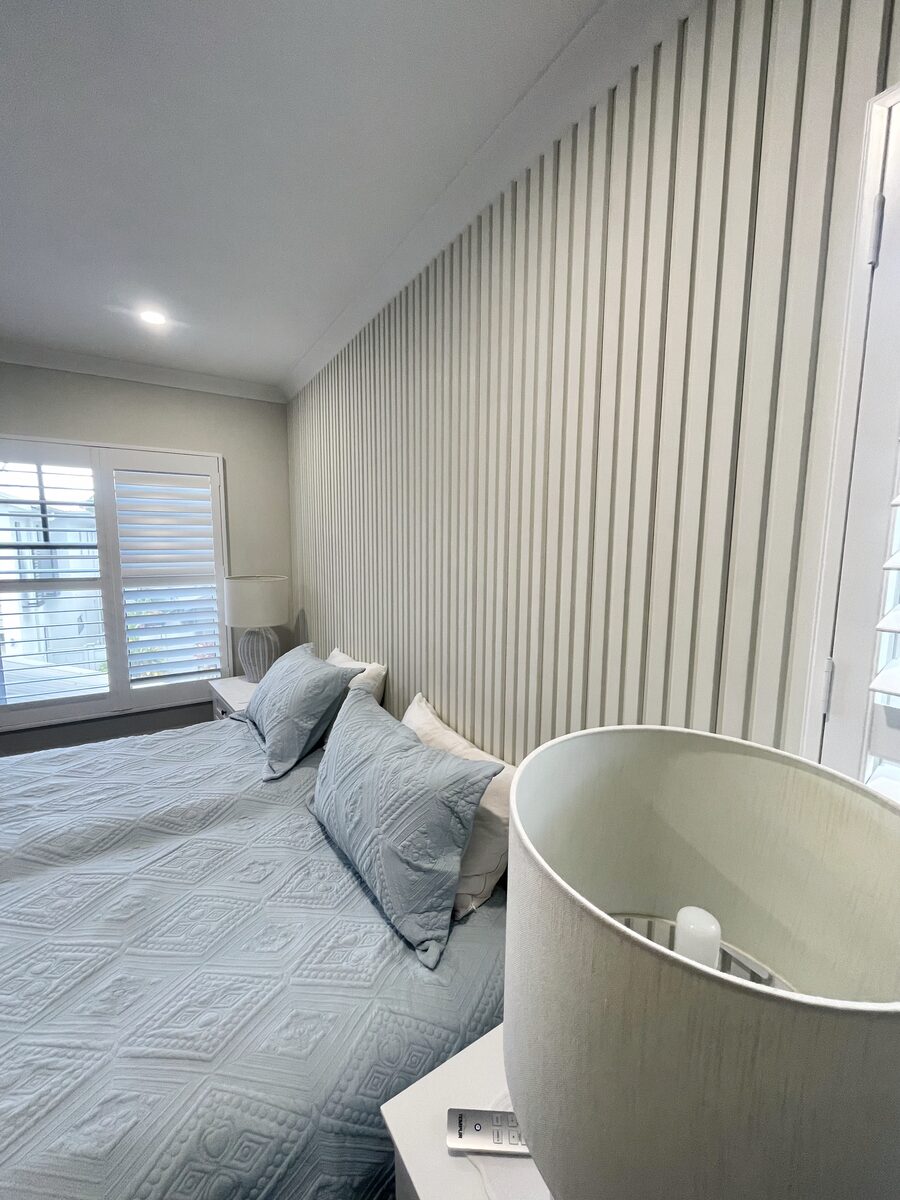 Wide view of the finished slat feature wall in a Brisbane bedroom, mitred neatly at the corners.