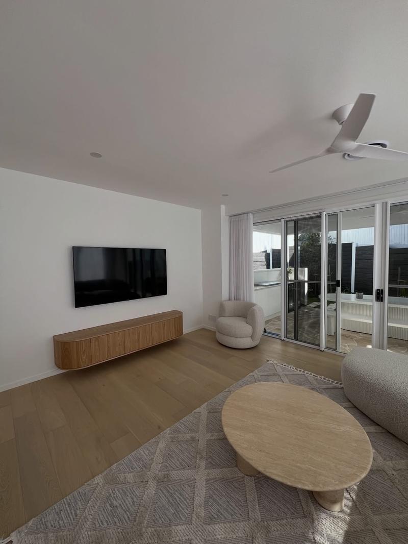 Wall-mounted TV above a floating timber console in a Brisbane living room.