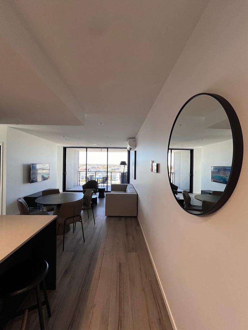 Tall arched mirror centred on a dining room wall, level with a long timber table.